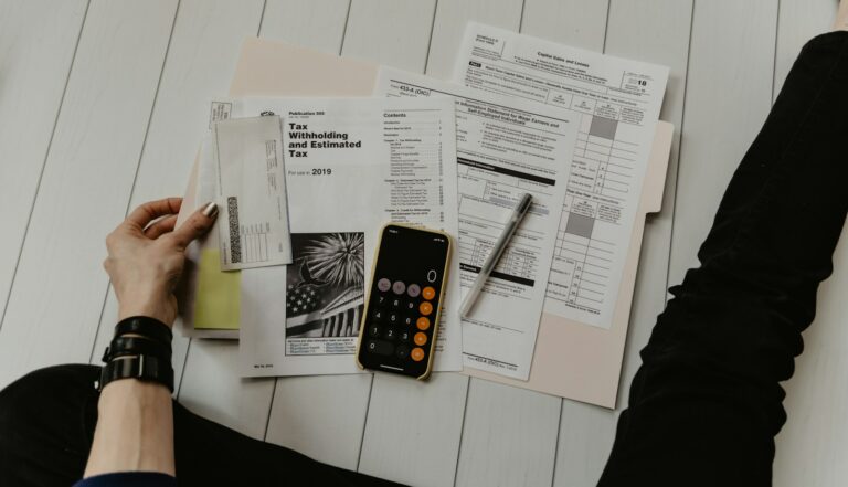 Manos de una persona revisando facturas sobre una mesa con una calculadora y un bolígrafo
