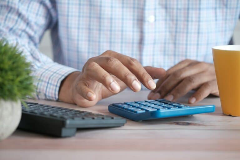 Dueño de un negocio calculando con una calculadora el coste mensual de una agencia de marketing digital
